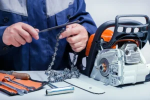 Person sharpening a chainsaw chain with a file next to the chainsaw and tools.